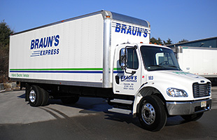 A photo of a white semi-truck with the side of the truck labeled "Braun's Express" in navy blue writing.