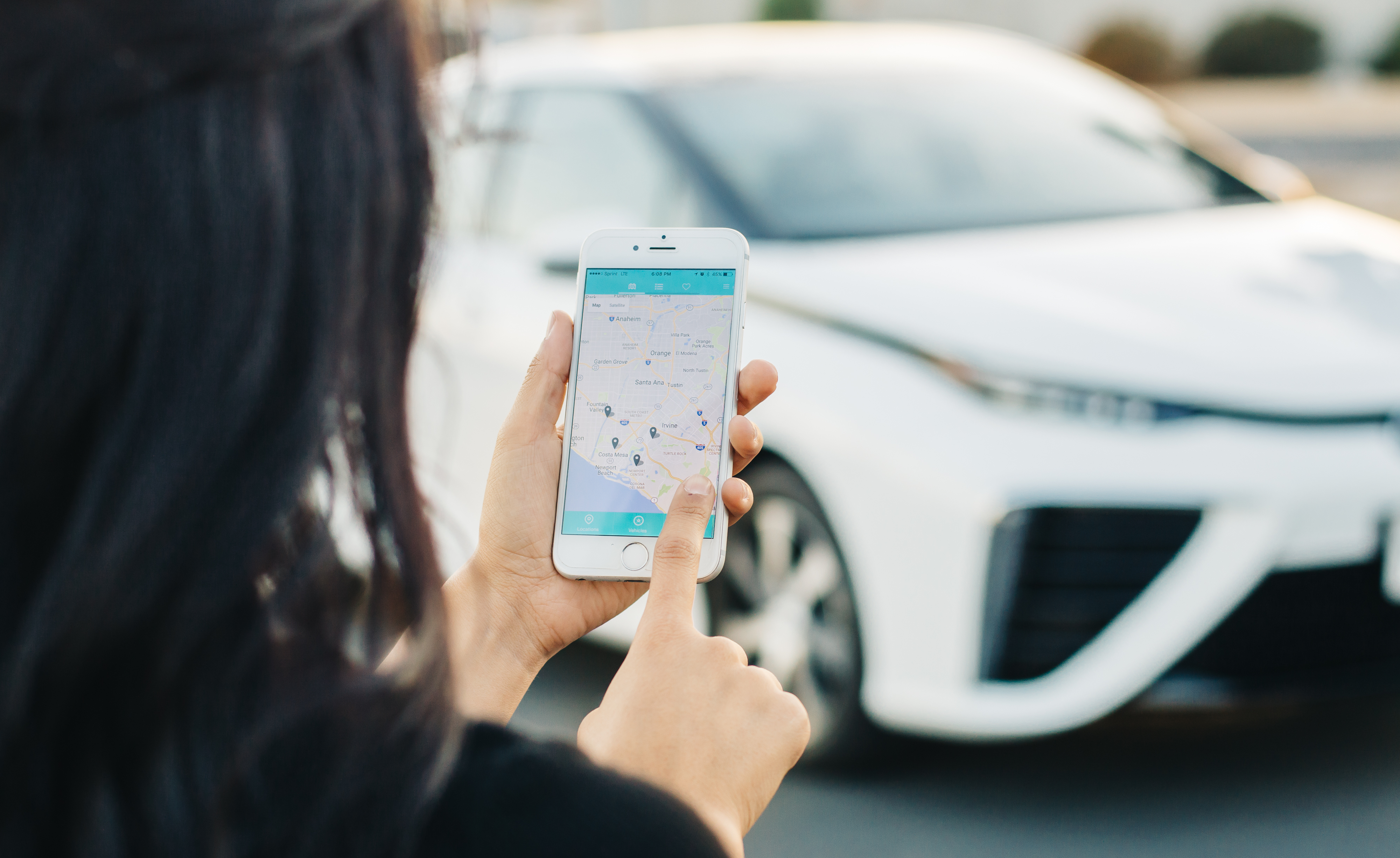 A woman uses a cell phone app to reserve a shared hydrogen fuel cell electric vehicle.