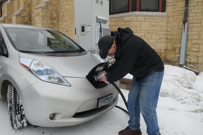 A man plugs in an electric vehicle in the snow