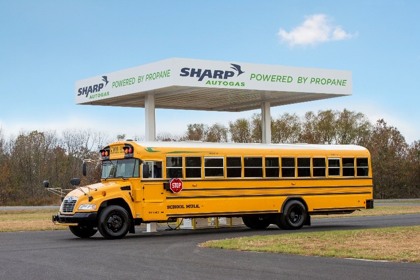 A propane school bus sits in front of a Sharp Autogas propane station.