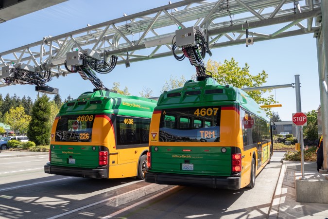 Two buses plugged into charging station